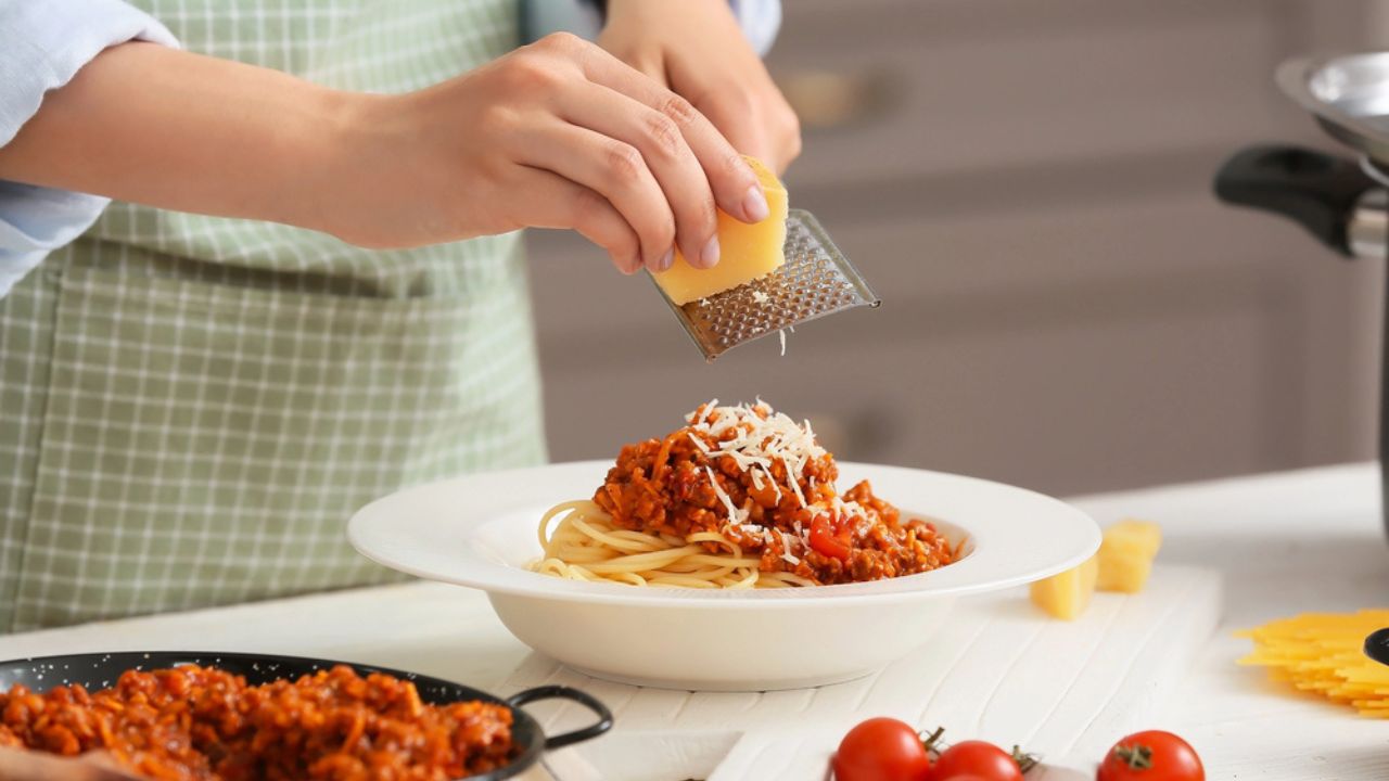 Woman cooking tasty pasta bolognese in kitchen, closeup