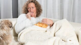 Woman eating chips and looking at dog