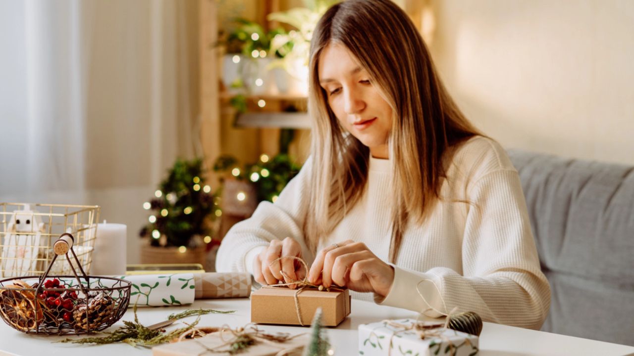Woman wrapping Christmas eco natural gift boxes at home