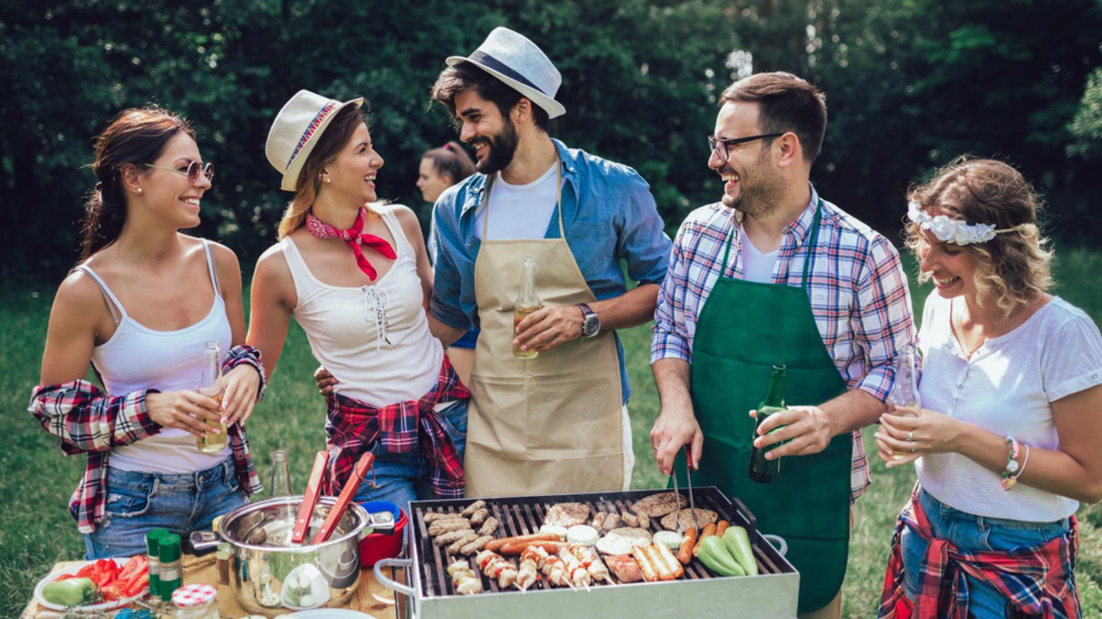 Young friends having fun grilling meat enjoying barbecue party