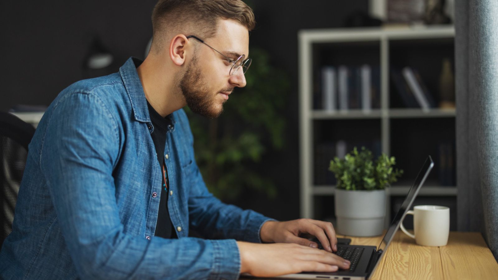 Young handsome bearded man writing code on laptop, programmer