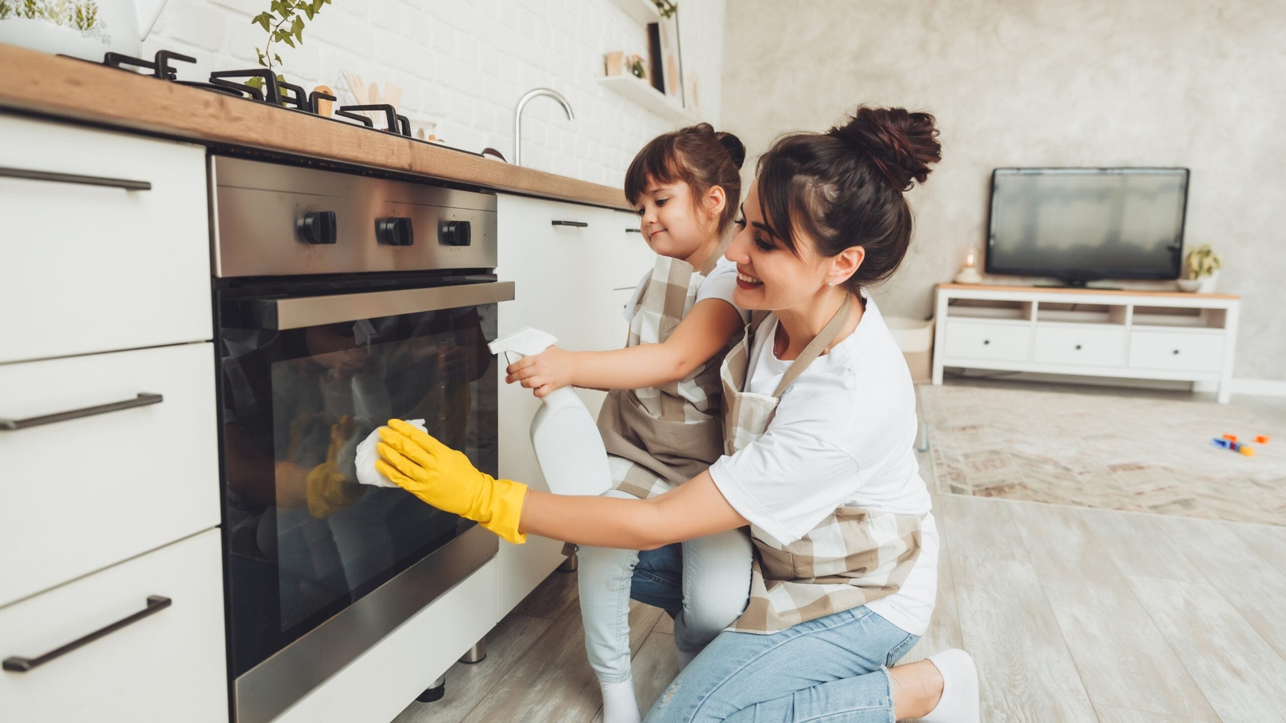 a mom and little girl clean the oven