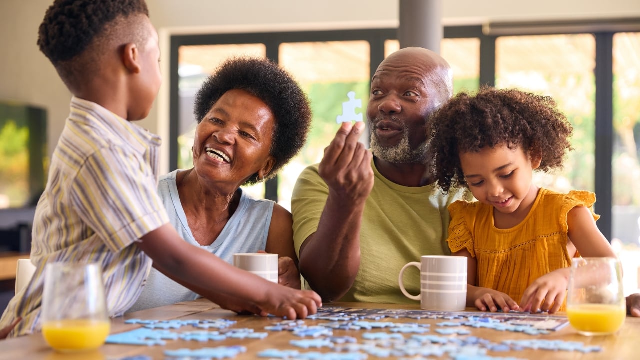 two kids with grandparents doing a jigsaw puzzle