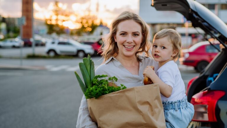a mom holding a grocery bag and a toddler