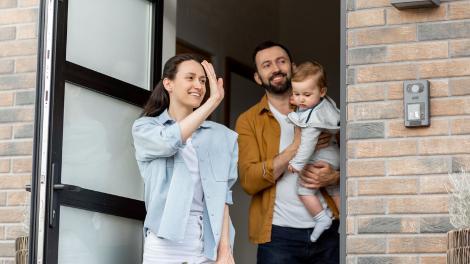 young parents family waving outside of front door house goodbye