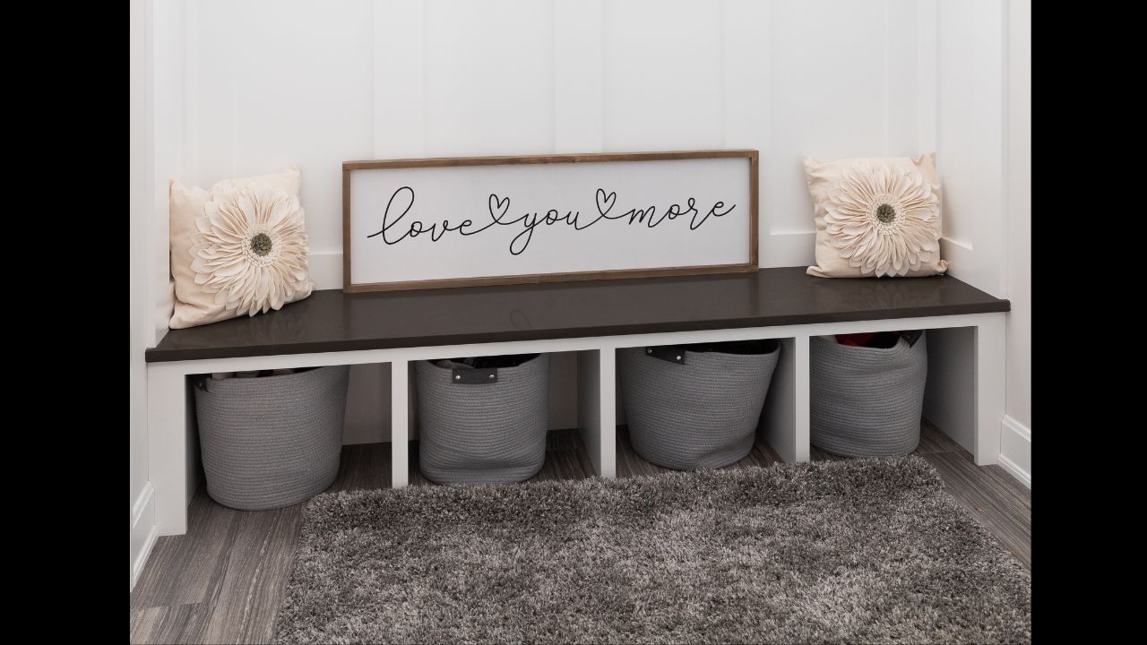 A cozy mudroom with hooks on board and batten walls, a wooden bench seat, and a rug on a tiled floor.