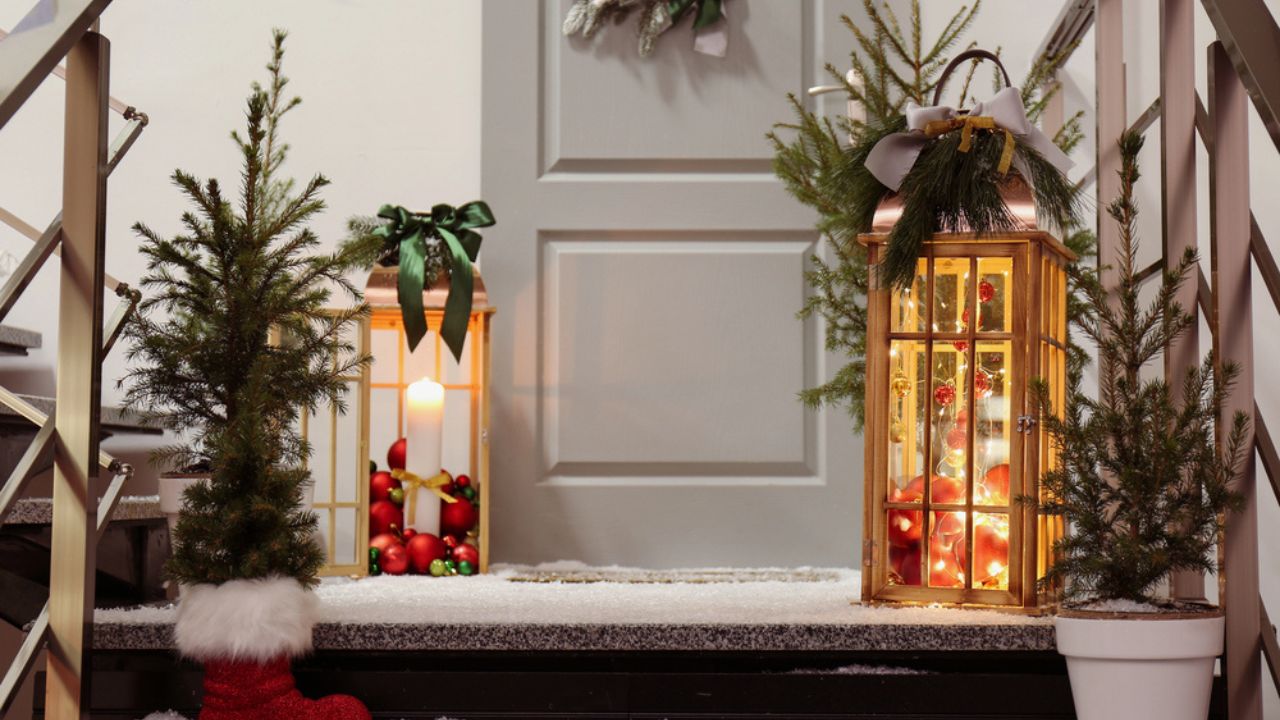 Decorative lanterns and small Christmas trees near house entrance
