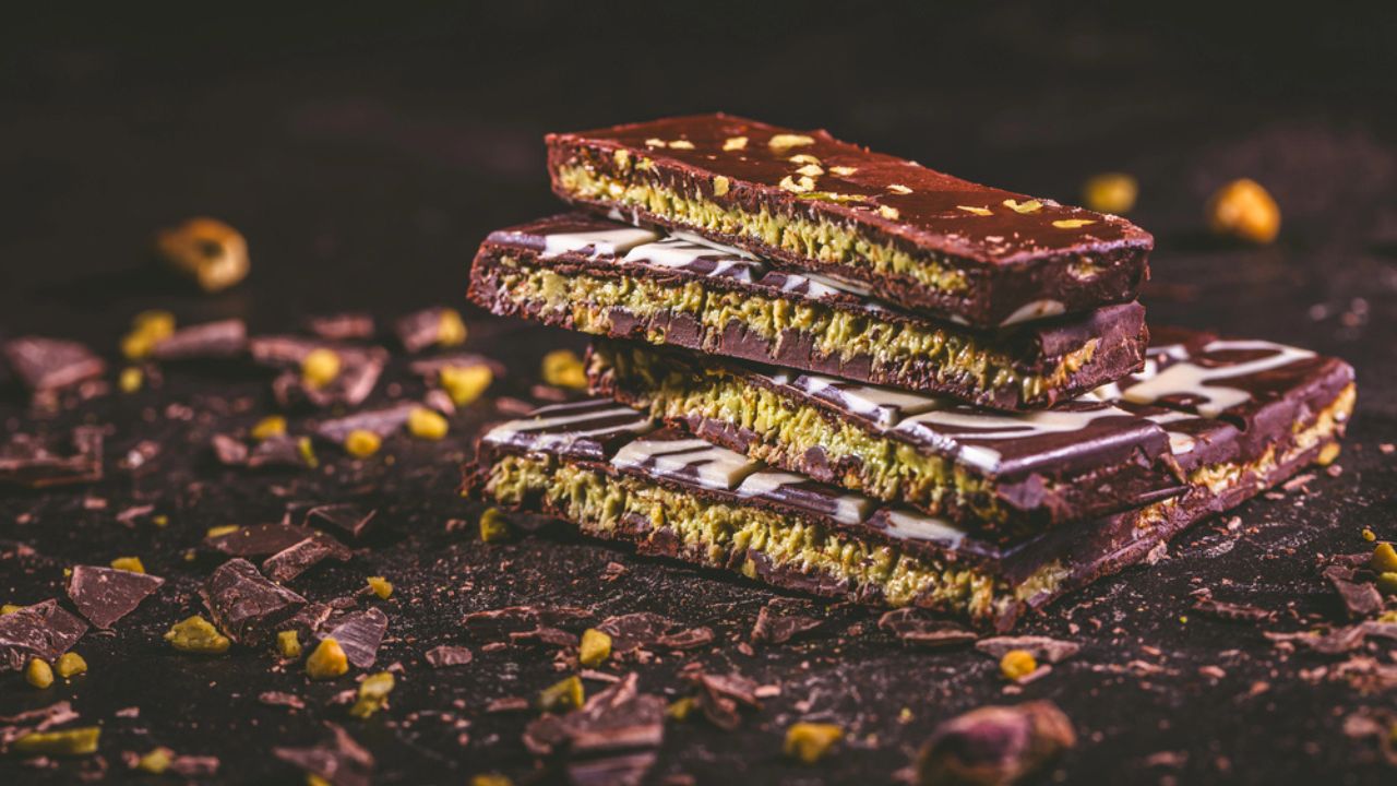 Dubai Chocolate bar with green kadayif and pistachio spread on brown background