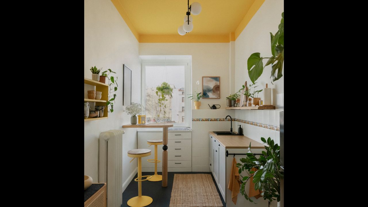 Eclectic kitchen interior with yellow ceiling, black floor and a mix of plants, textures and cheerful tones.