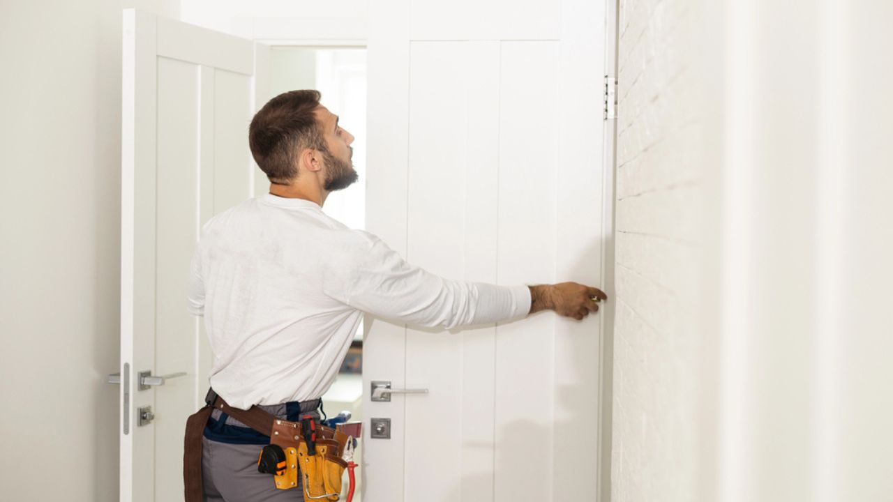 High Angle View Of Male Carpenter With Screwdriver Fixing Door Lock
