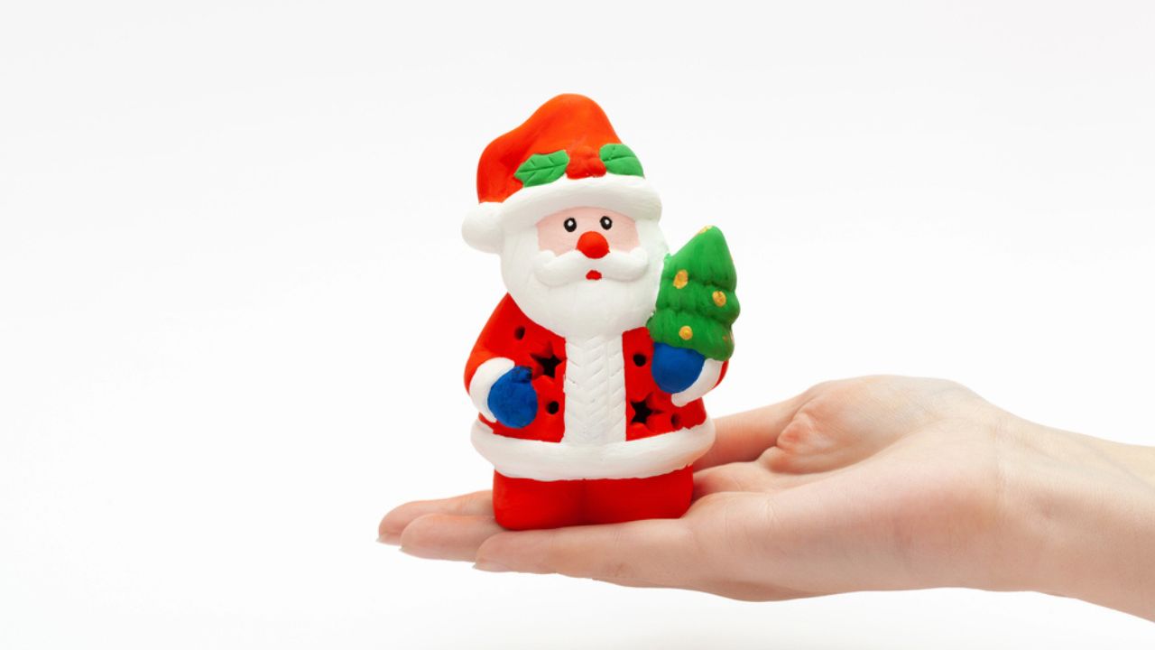 Little Santa Claus toy on the womans hand isolated on white background