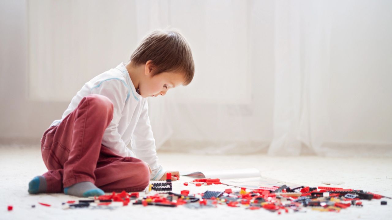Little child playing with lots of colorful plastic blocks indoor