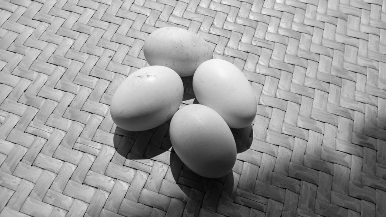 Photo of 4 chicken eggs on a black and white theme on a background of woven bamboo