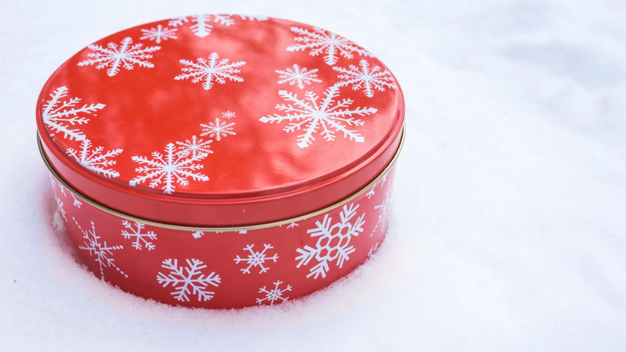 Round, red cookie and baked goods aluminum tin container decorated with white snowflake print pattern