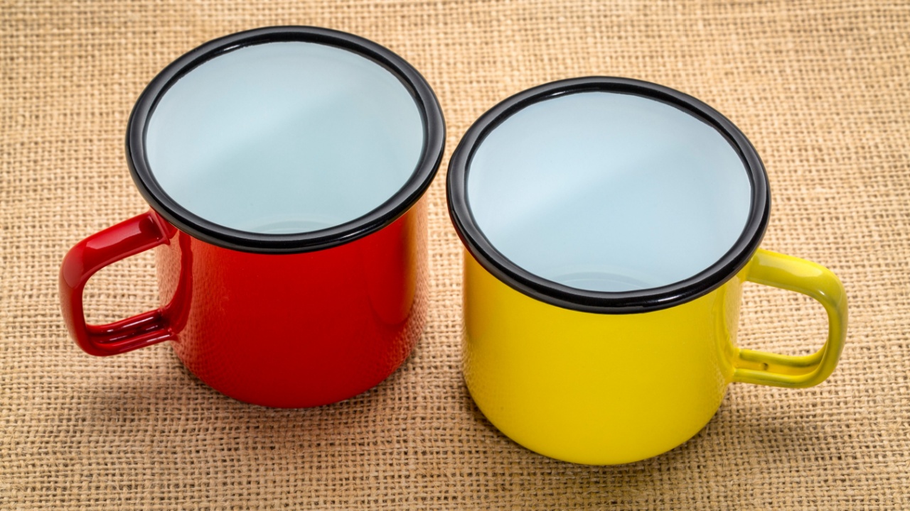 two empty metal enamel cups against burlap canvas