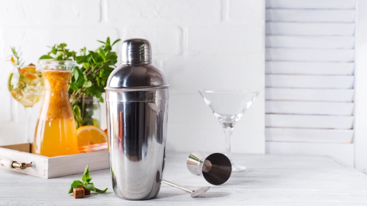 Cocktail shaker, swizzle, tongs and spoon with ice in a bucket for preparing a summer cocktail