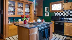Dayton, Ohio, USA - June 18, 2018: Green kitchen with built-in china cabinet, center island, black & white themed decor & back stairway in an hundred-year-old house.