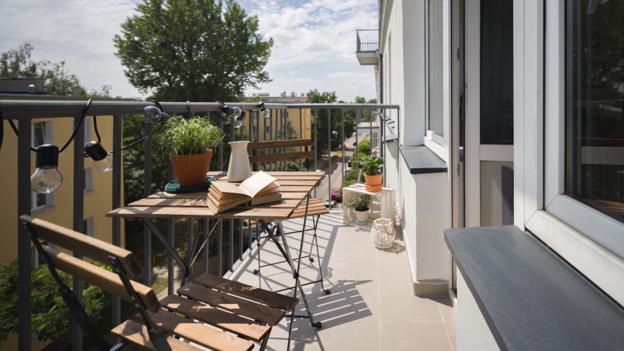 Leisure area on a balcony in a city apartment with wooden table and chairs