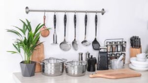 Set of clean cookware, dishes, utensils and appliance on table at white wall