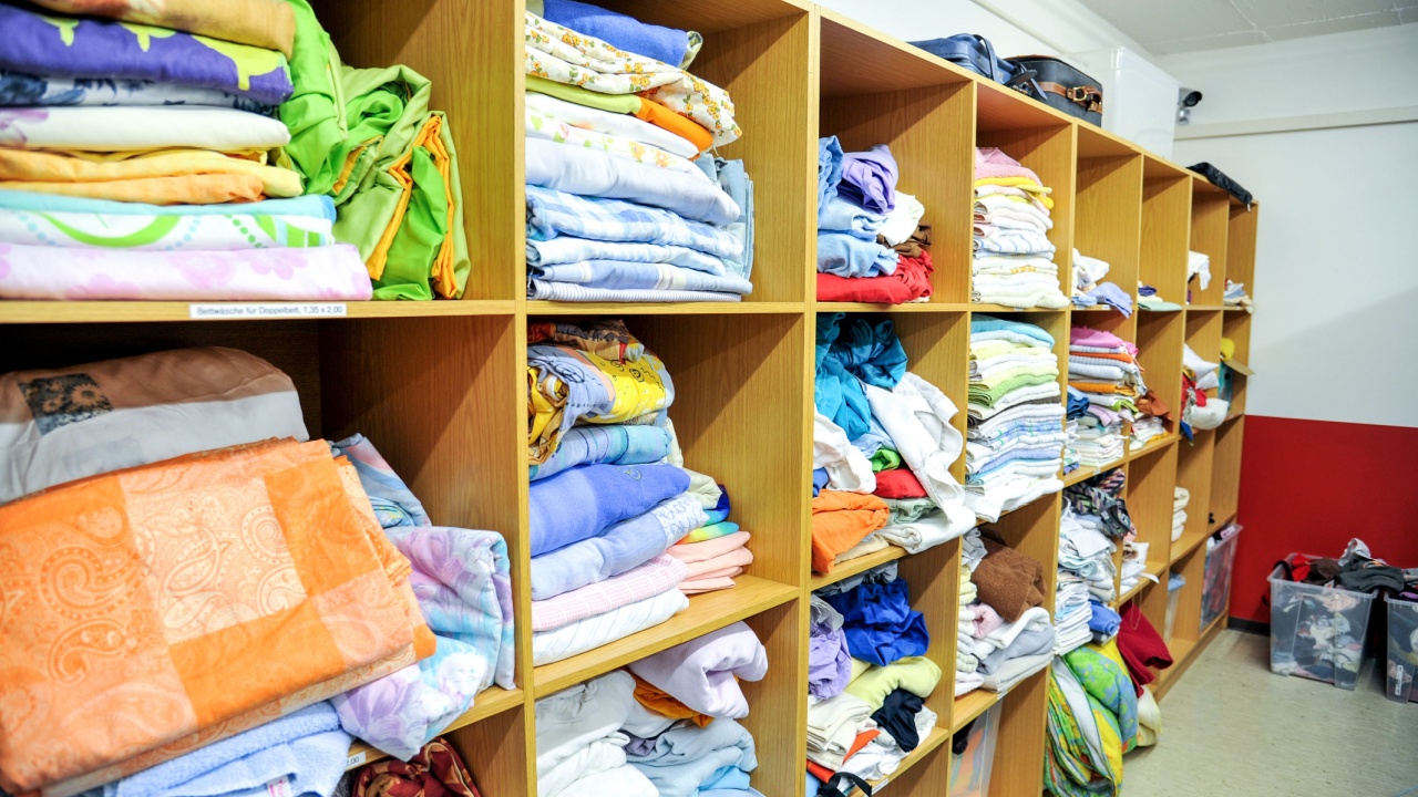 Large selection of different used textiles, towels linen, bedclothes, in a second hand shop or thrift store - selective focus
