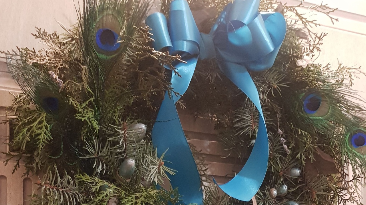Handmade Christmas door wreath with peacock feathers and blue ribbon bow. Christmas arrangements on patterned door panel background. Winter holiday home decor. New Year decoration