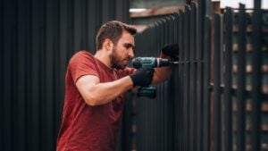 Industry construction site - details of man installing metal elements on outdoor fence.