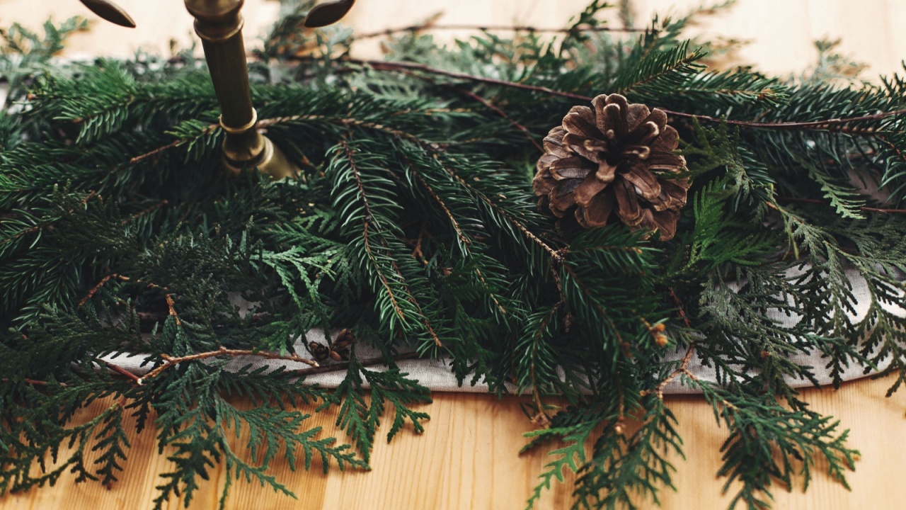 Stylish rustic christmas arrangement for festive dinner closeup. Fir branches with pine cones and vintage candlestick with candles on linen cloth on wooden table. Christmas rural decor