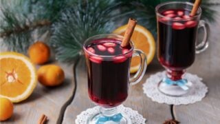 Two glasses of Scandinavian mulled wine Glogg garnished with stick of cinnamon and almonds