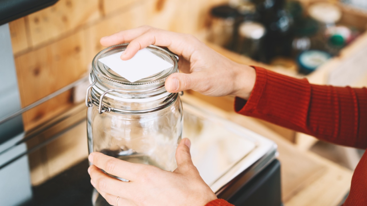 Woman chooses and buys products in zero waste shop. Weighing dry goods in plastic free grocery store. Girl with cotton reusable bag weigh glass jars on scales. Eco shopping at local business