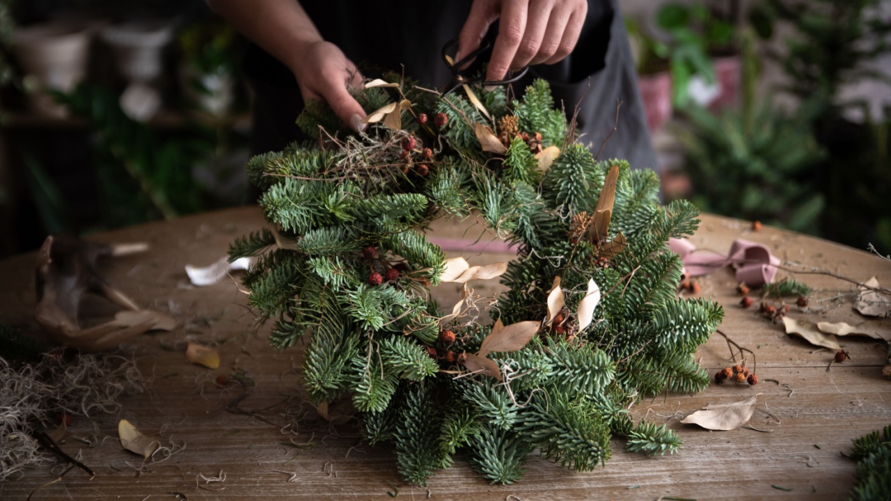 Woman making Christmas wreath of spruce, step by step. Concept of florist's work before the Christmas holidays.