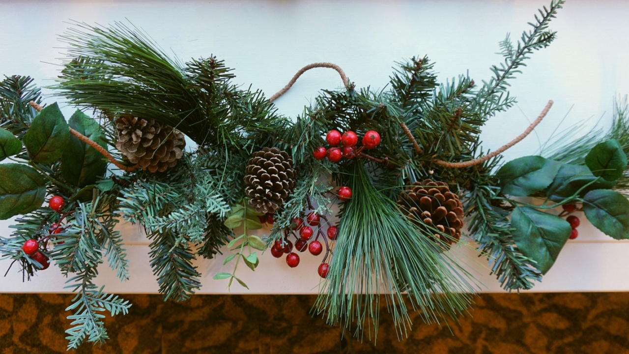 a window sill decorated with evergreen branches, pine cones and red berries