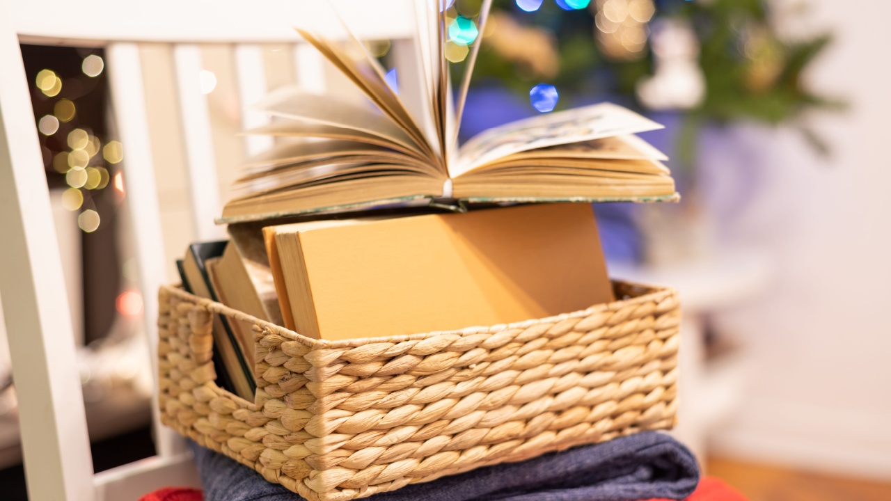 Books, warm sweaters and open book on festive bokeh background. Concept reading, cozy home, holidays