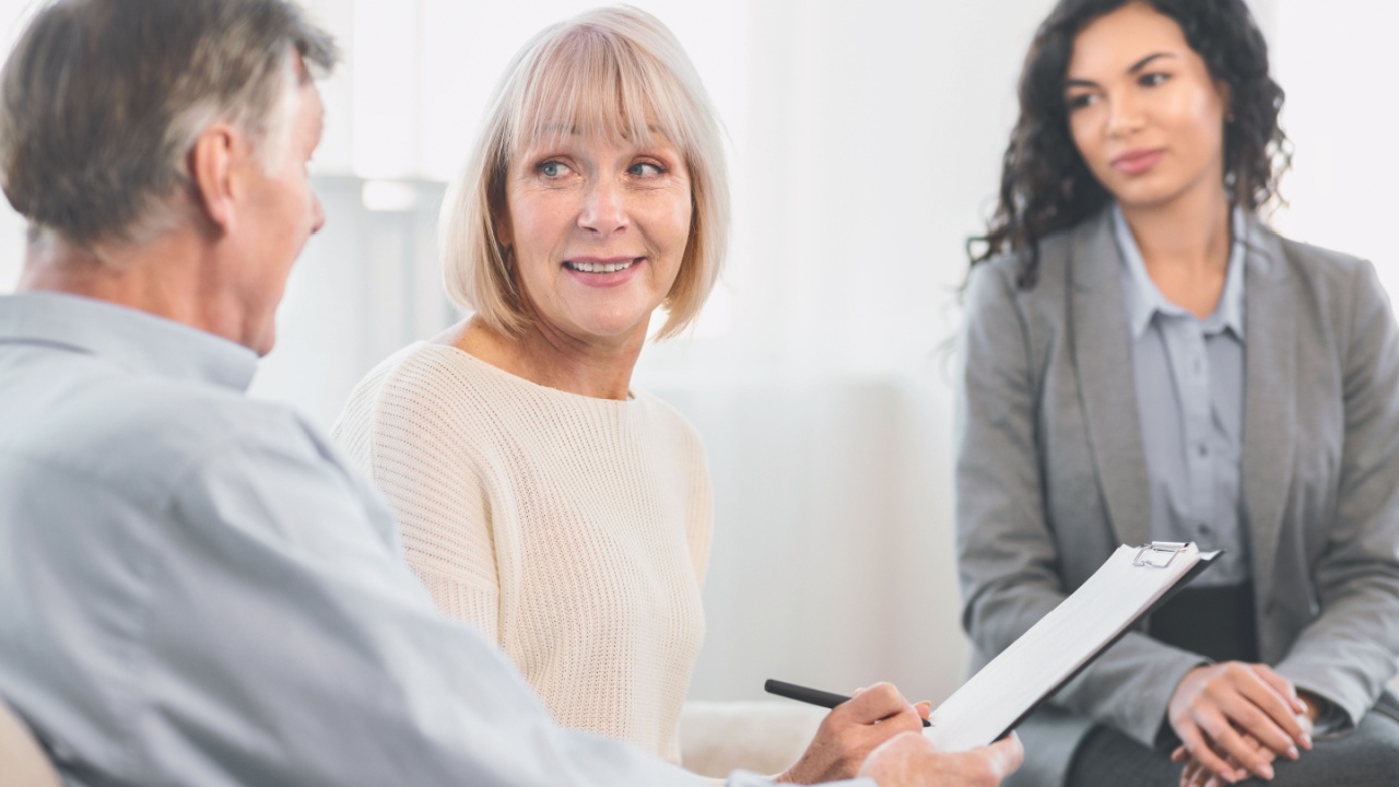 Senior Health Insurance Concept. Mature couple making agreement with sale agent, senior woman signing contract