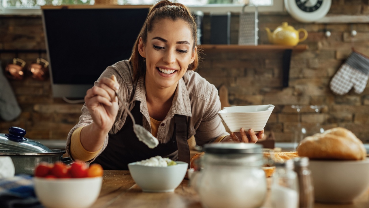 Young happy woman preparing dipping sauce while cooking in the kitchen.