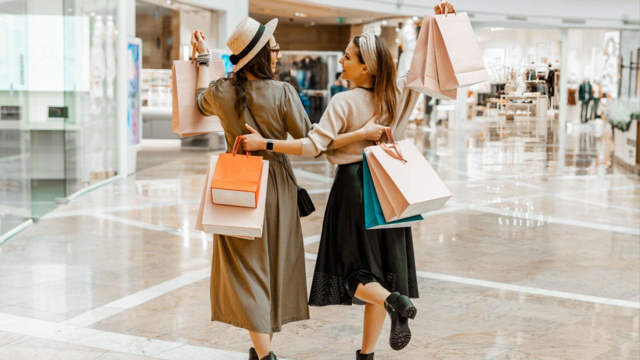 Shopping and entertainment, mall inside. Two beautiful girls with paper bags at the mall. The joy of consumption,