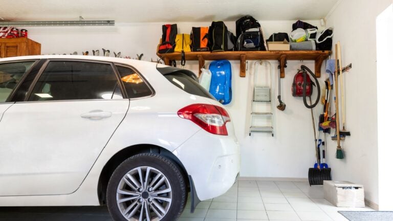 Home suburban car garage interior with wooden shelf , tools and equipment stuff storage warehouse on white wall indoors. Vehicle parked at house parking