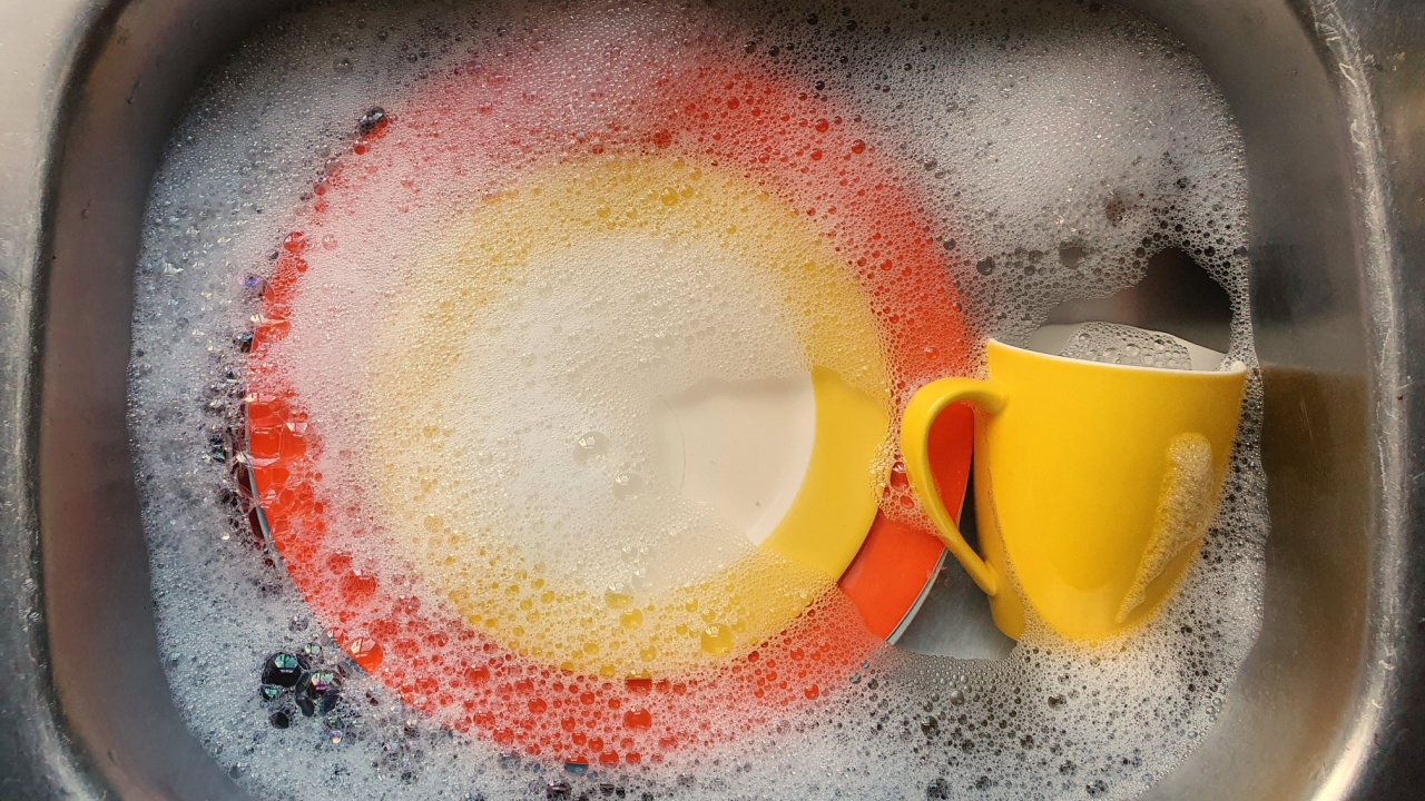 Colourful dishes soaking in soapy water, in kitchen sink.