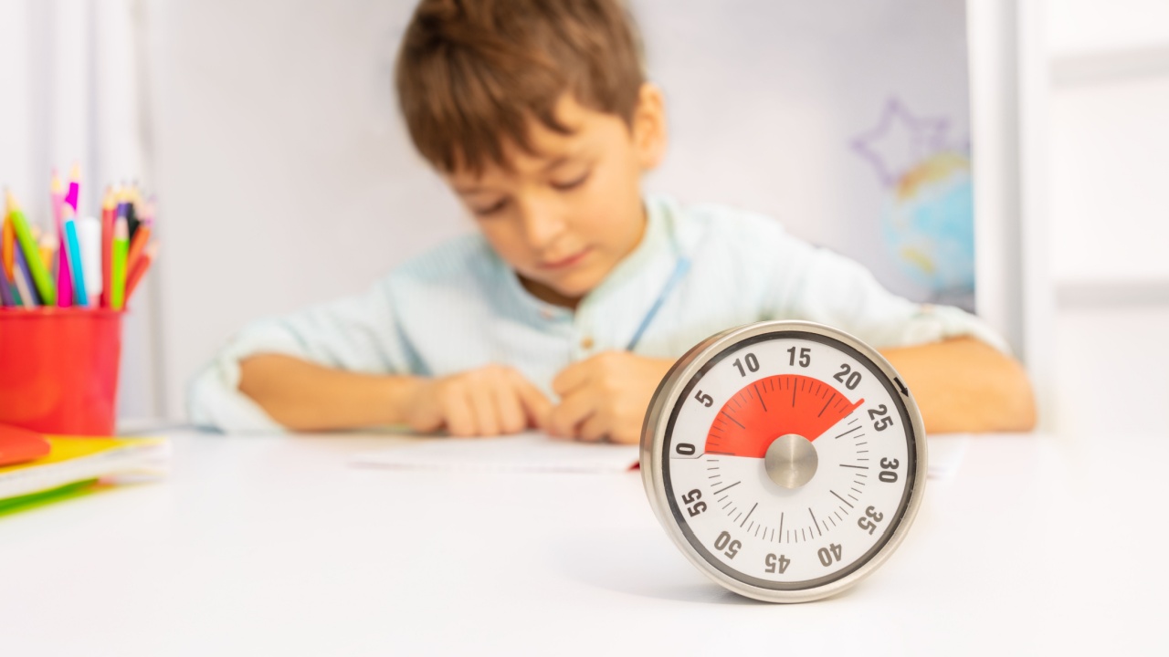 Timer and little boy during development therapy lesson draw on paper on background