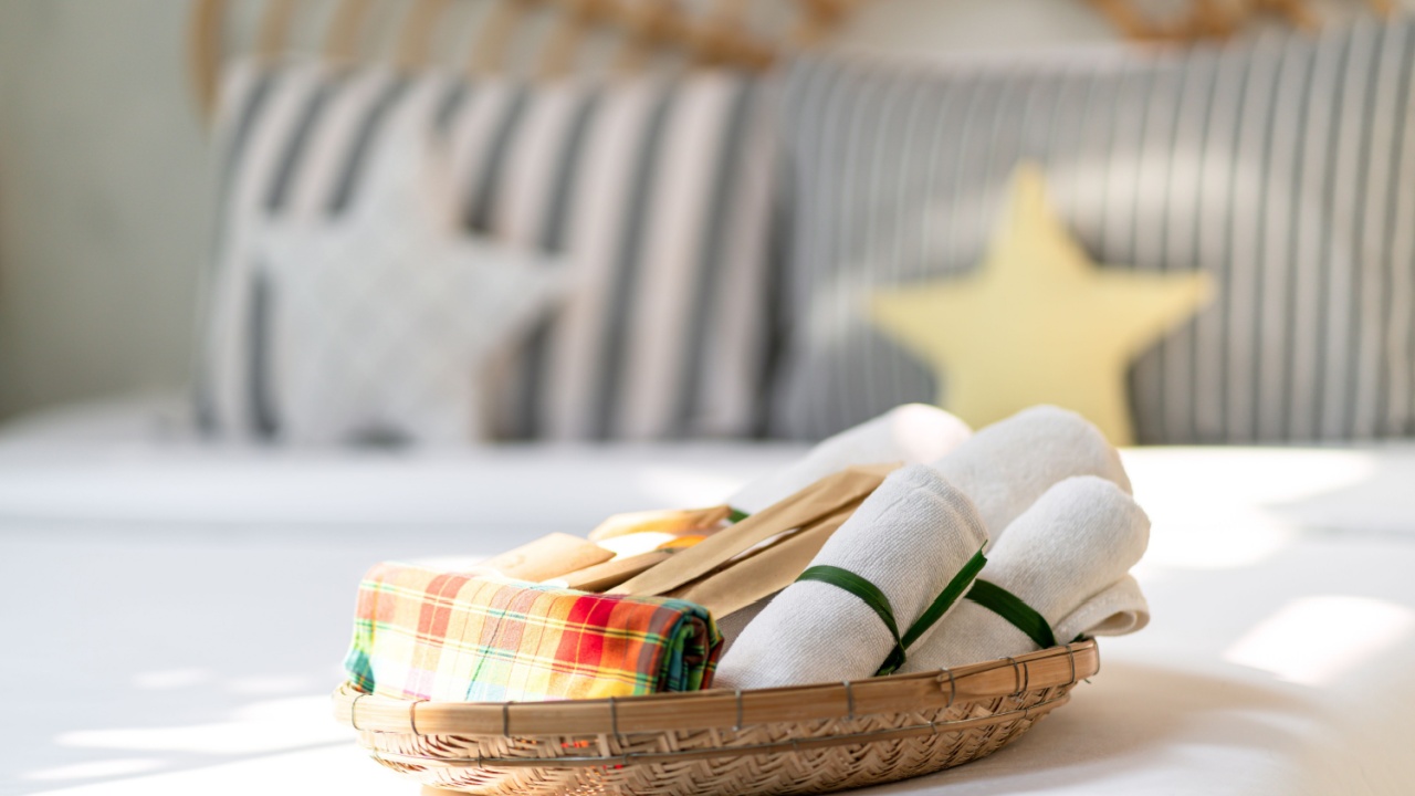 White towel in woven basket on bed in guest room for resort customer