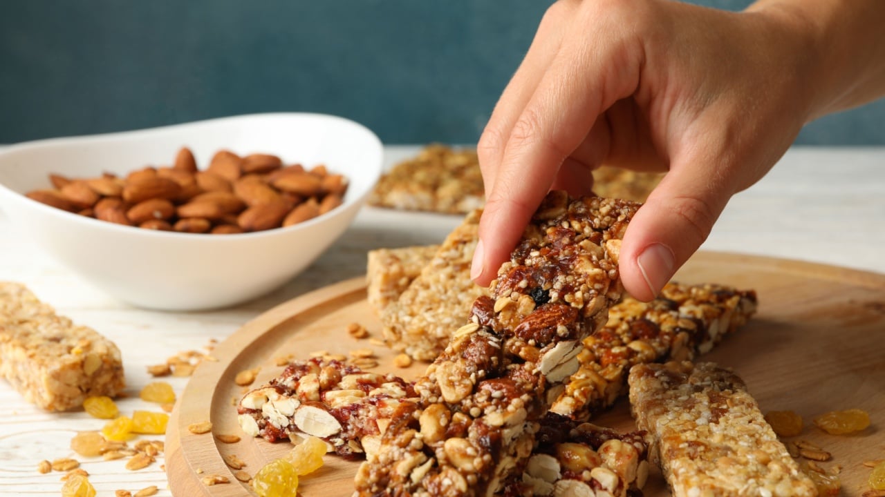 Female hand hold granola bar on wooden background with granola bars