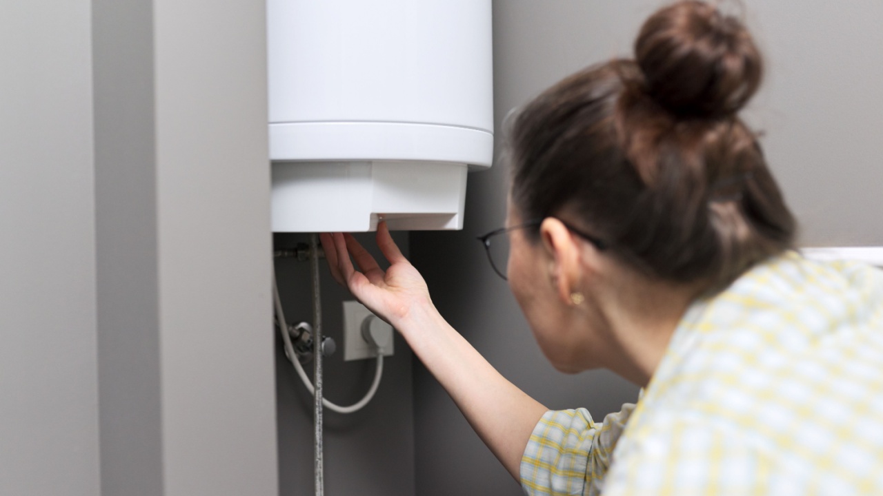 Home water heater, a woman regulates the temperature on an electric water heater, comfort and hot water in the house