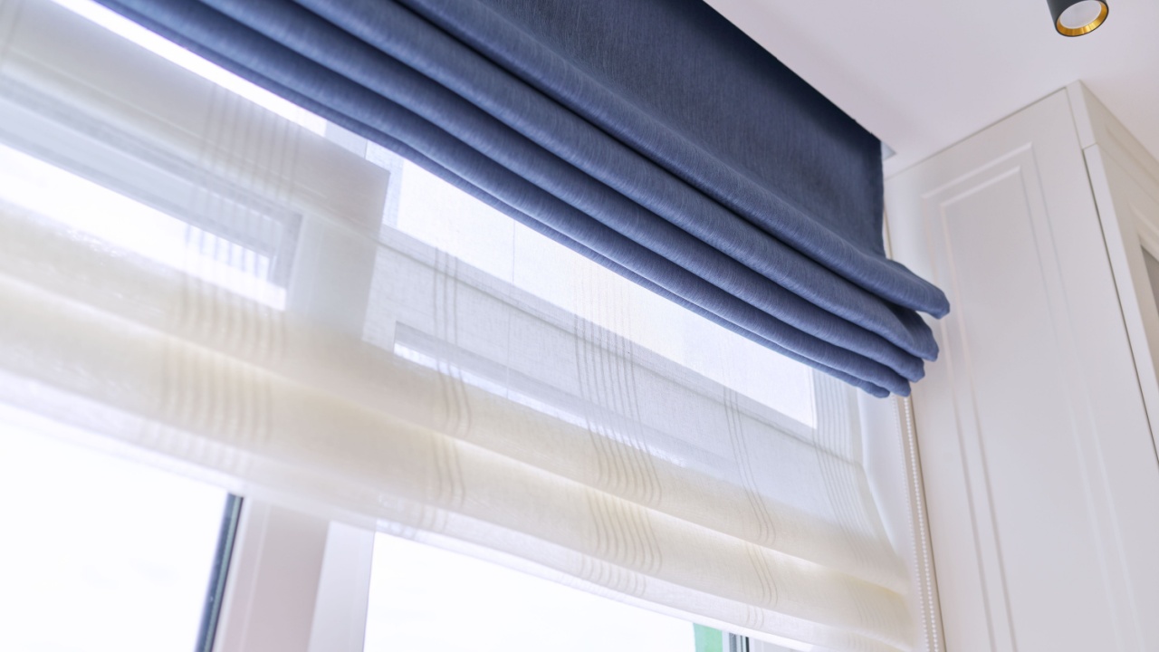 Roman blind in the interior detail close-up. Curtain blue blackout fabric, sheers white linen, fashionable modern window decoration design at home