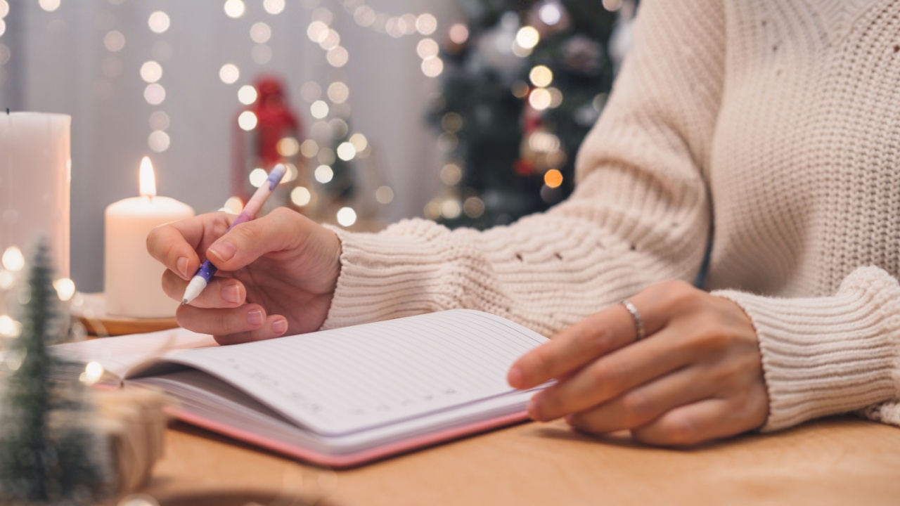 Goals plans make to do and wish list for new year christmas concept writing in notebook. Woman hand holding pen on notepad at home on winter holidays xmas.
