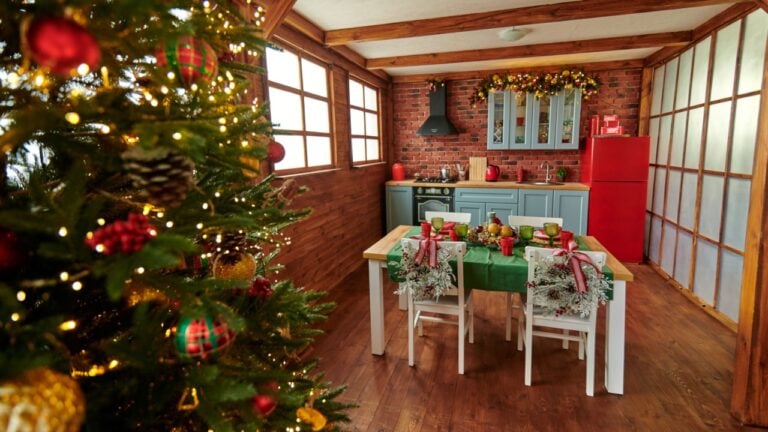 New Year's blue kitchen with a served Christmas table, green tablecloth, plates and white chairs. Red fridge and black hood
