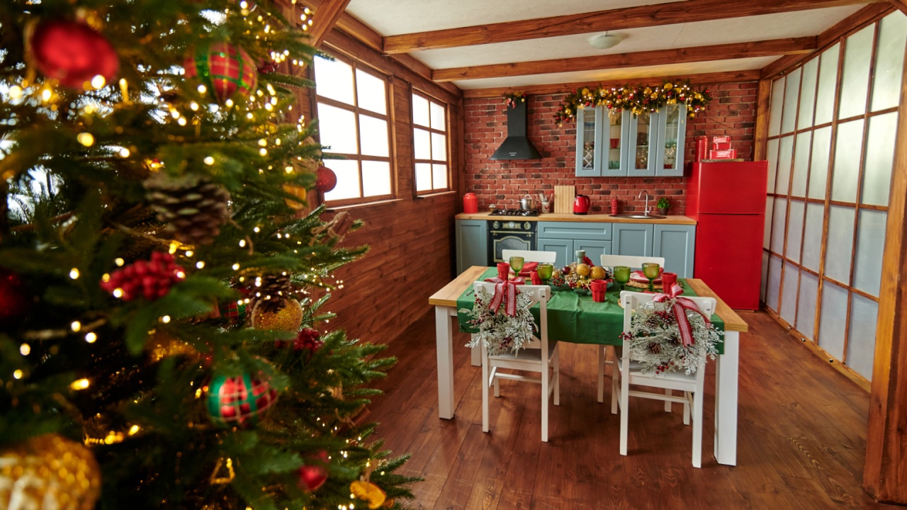 New Year's blue kitchen with a served Christmas table, green tablecloth, plates and white chairs. Red fridge and black hood
