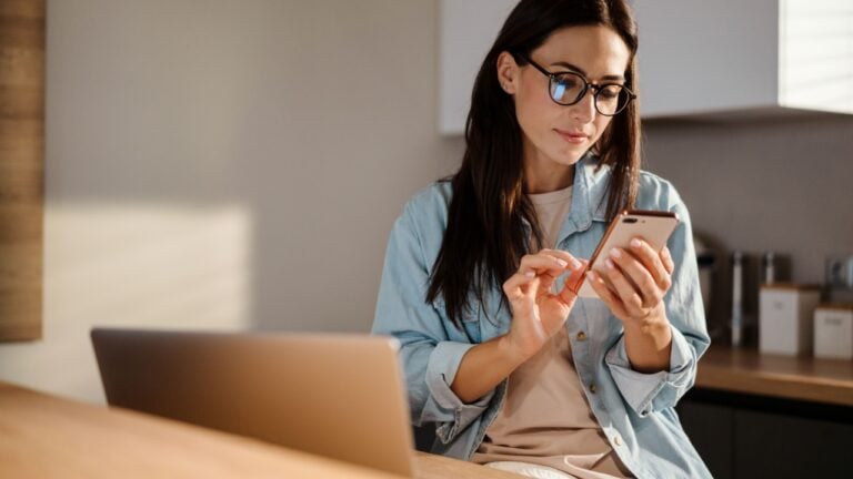 Beautiful woman using mobile phone and laptop computer at home