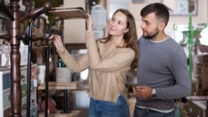 Loving couple looking for hallstand in shop of secondhand furniture