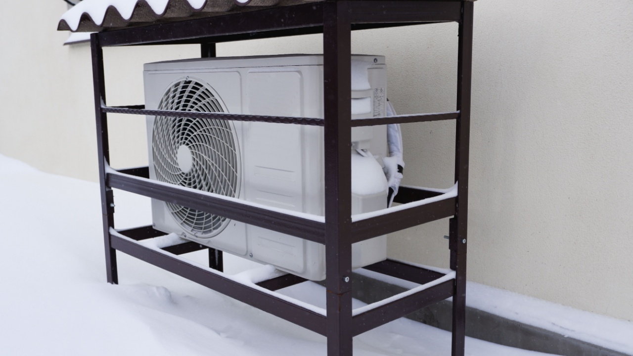 The outdoor unit of the air conditioner (air-to-air heat pump) in the snow during winter operation.