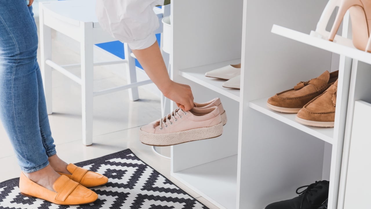 Woman taking shoes from stand in hall