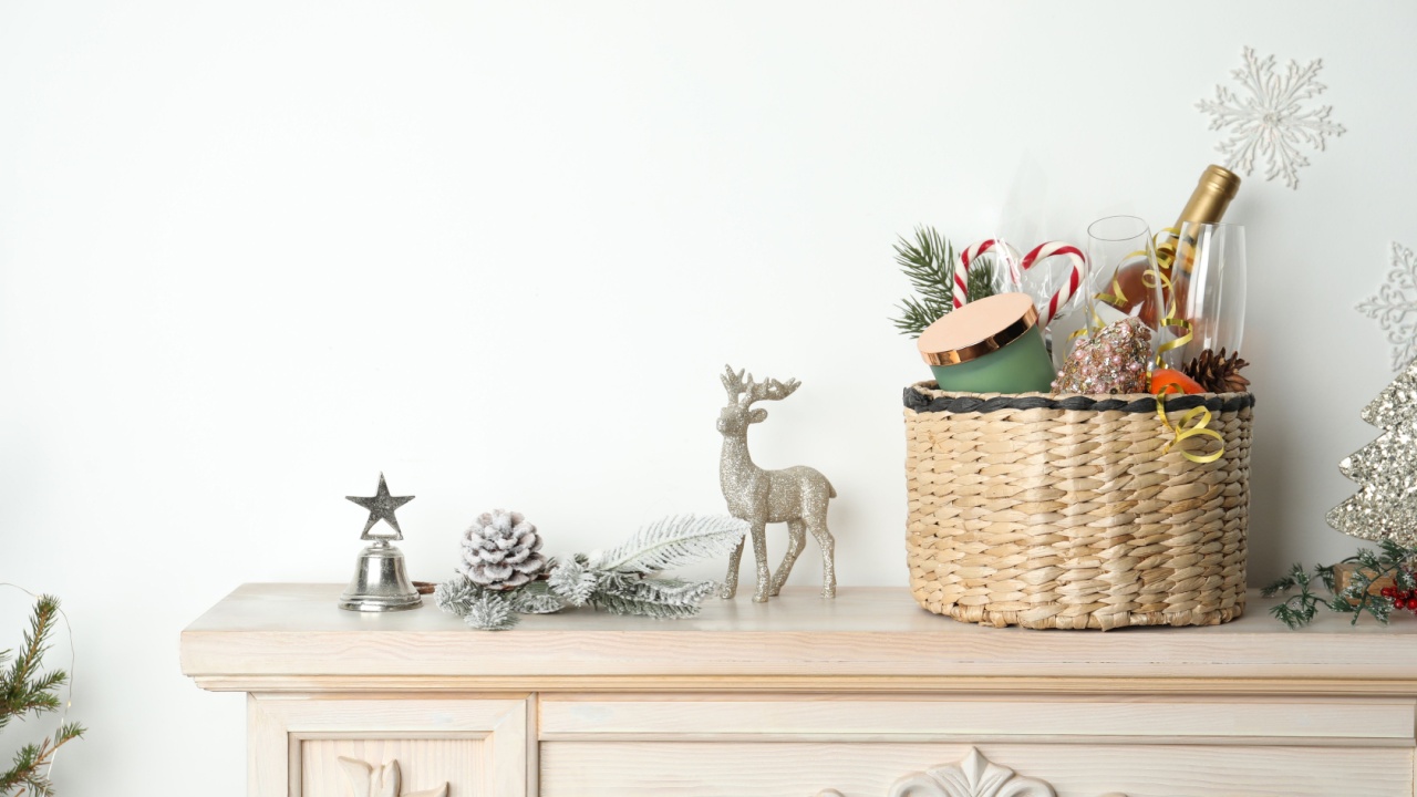 Wicker basket with gift set and Christmas decor on shelf. Space for text